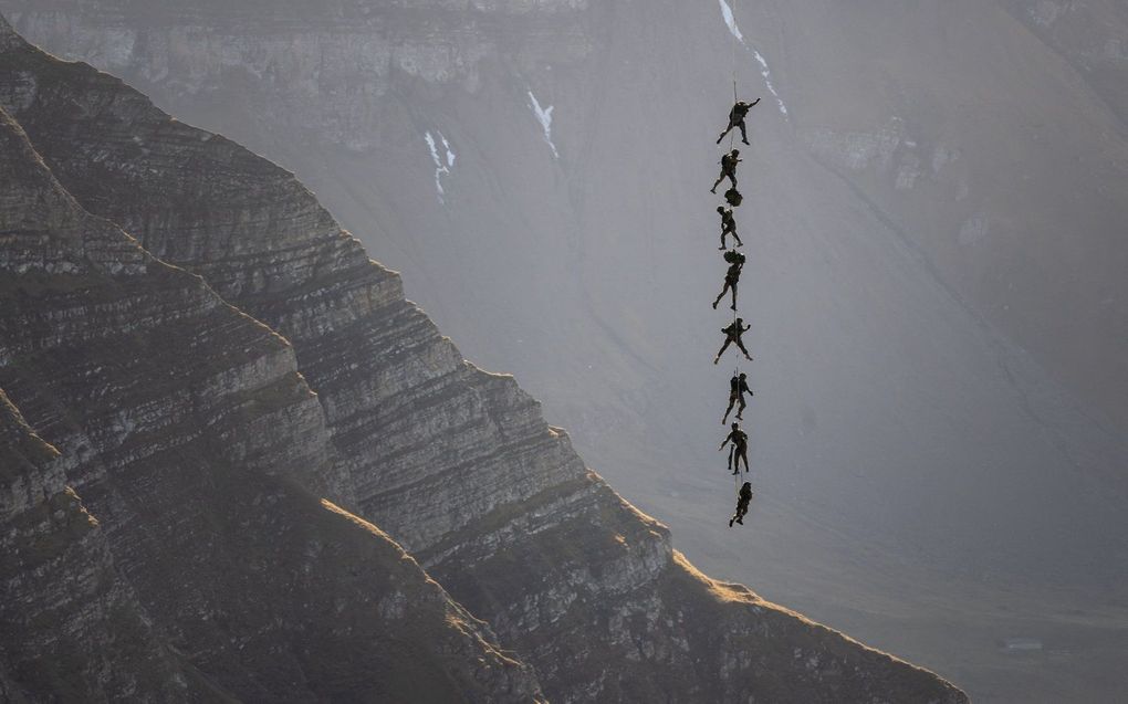 Soldaten van het Zwitserse commando van de special forces treden op, hangend aan een helikopter, tijdens het jaarlijkse live vuur evenement boven de Axalp in het Berner Oberland, Zwitserland. beeld AFP, Fabrice Coffrini