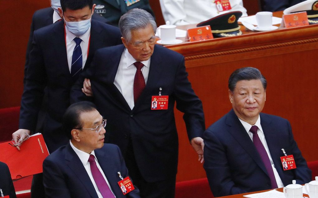 De voormalige president van China Hu Jintao (m) wordt naar buiten geleid door een steward terwijl president Xi Jinping (r.) en Premier Li Keqiang (l.) toekijken tijdens de slotceremonie van het 20e Nationale Congres van de Communistische Partij van China (CPC) in Peking, China. beeld EPA, Mark R. Christino