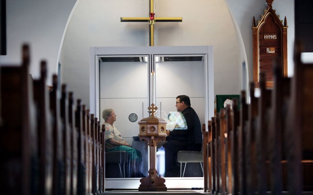 Een Lutherse kerk in Ottawa, Canada, maakte tijdens de coronapandemie gebruik van een glazen ruimte om besmetting te voorkomen. beeld AFP, Dave Chan