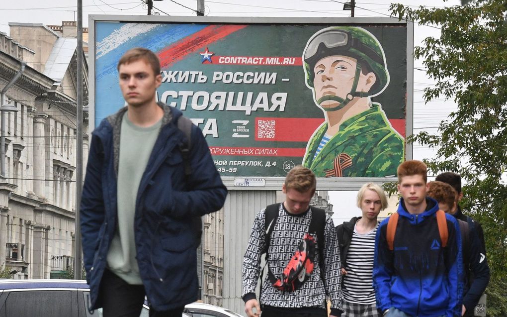 Jongeren lopen langs een billboard dat oproept te dienen in het Russische leger. beeld AFP, Olga MALTSEVA