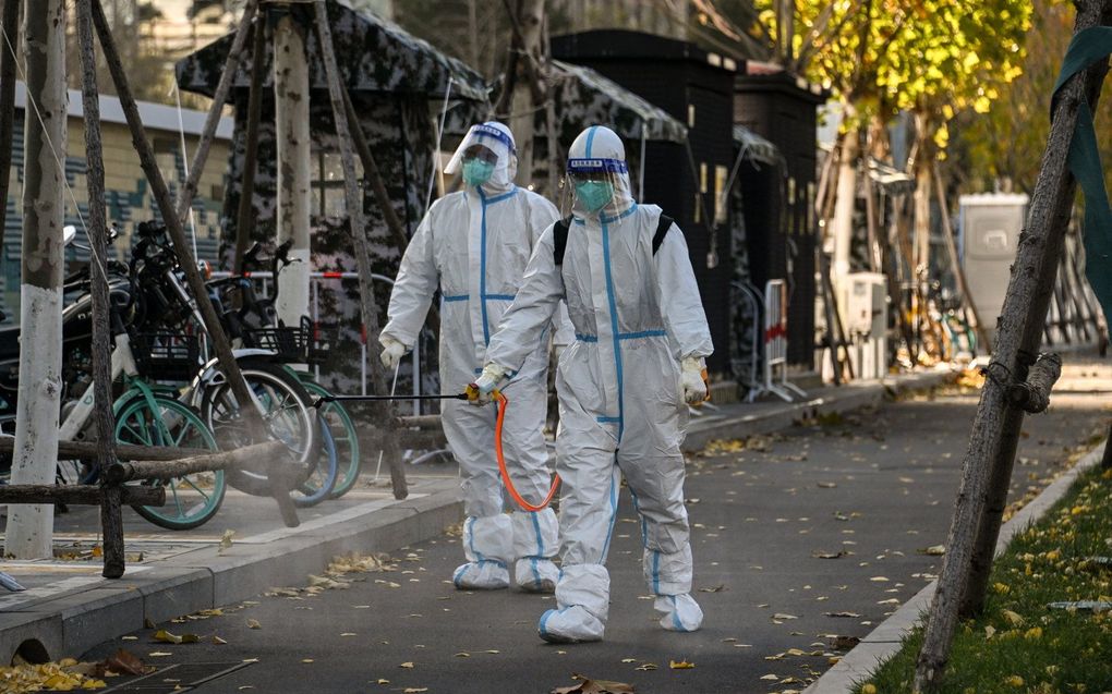 Werknemers met persoonlijke beschermingsmiddelen ontsmetten een gebied in de buurt van een woonwijk onder lockdown. beeld AFP, Noel Celis