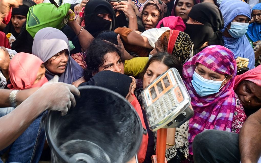 „In Dhaka krioelt het van de mensen, die niet leven maar overleven.” Foto: in de rij voor door de overheid gesubsidieerd voedsel. beeld AFP, Munir Uz Zaman