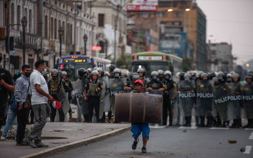 Leden van de politie houden demonstranten in bedwang in Lima, waar de afgezette president Pedro Castillo vastgehouden wordt. Voor- en tegenstanders van Castillo raakten met elkaar slaags. beeld EPA,  Aldair Mejia