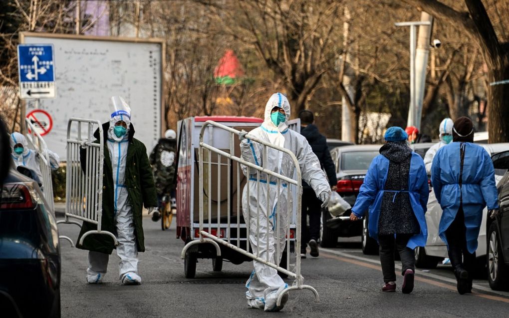 Chinese gezondheidswerkers sjouwen met barricades in een wijk in Peking die net is geopend na een afsluiting vanwege Covid-19-besmettingen. beeld AFP, Noel Celis