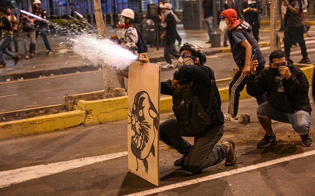 Aanhangers van de voormalige president Pedro Castillo werpen vuurwerk naar de oproerpolitie. beeld AFP,ERNESTO BENAVIDES