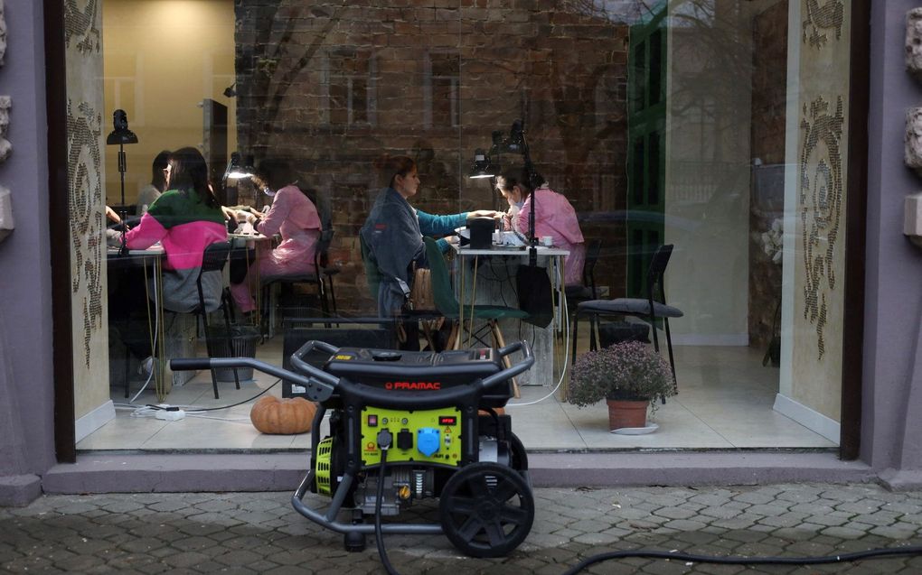 Mensen zitten in een nagelstudio in Odessa, terwijl een generator zorgt voor de energievoorziening. Beeld AFP, Oleksandr GIMANOV