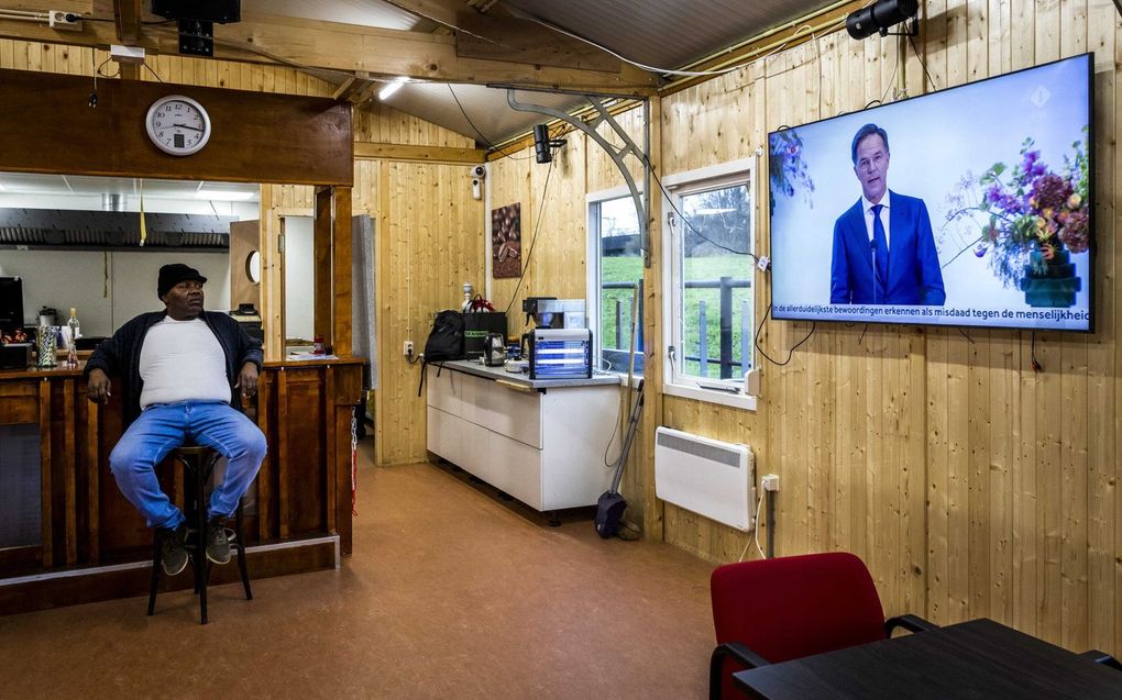 Een Surinamer kijkt in buurthuis Torioso in de Bijlmer naar de toespraak van minister-president Mark Rutte in het Nationaal Archief in Den Haag. beeld ANP REMKO DE WAAL