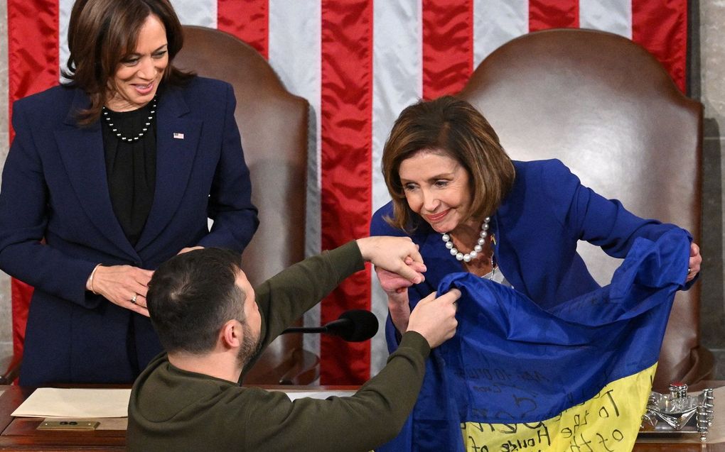 Zelenski biedt Pelosi en Kamala Harris een strijdvlag aan. Beeld AFP, Jim WATSON