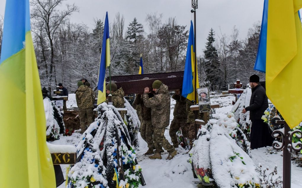 Oekraïense militairen dragen de kist met een gesneuvelde krijgsmakker naar het graf.. beeld EPA, Oleg Petrasiuk