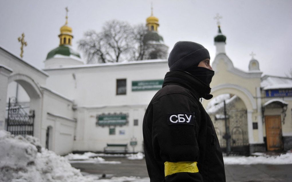 Een agent van de Oekraïense veiligheidsdienst SBU stat voor de Kiev-Petsjersk Lavra of Holenklooster tijdens een huiszoeking. beeld AFP, Sergei Chuzavkov