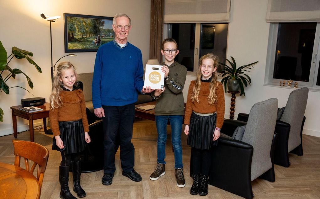 Lianne den Besten (l.) overhandigt samen met haar broertje Rens en zusje Hannah een notenpakket aan Dick Vis, conciërge van hun basisschool. „Meneer Vis lacht altijd.” beeld Cees van der Wal