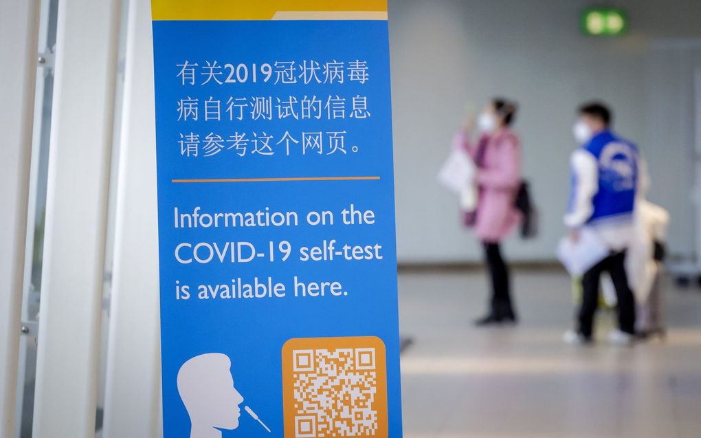 Reizigers uit China lopen langs een banner met informatie en krijgen een gratis coronazelftest bij aankomst op Schiphol. beeld ANP, Robin van Lonkhuijsen