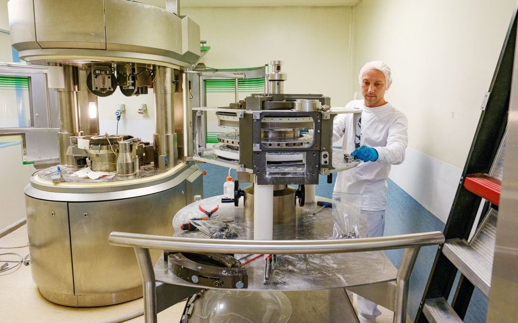 Een medewerker van medicijnfabriek InnoGenerics maakt een machine schoon waarmee pillen worden gevormd. beeld ANP, Marlies Wessels