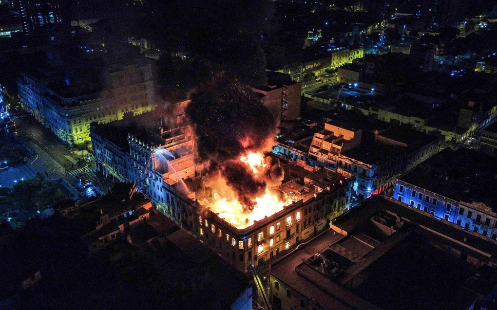 Een brand brandt in een herenhuis bij het historische Plaza San Martin in Lima, waar anti-regerings demonstranten eerder op de dag in botsing kwamen met de politie. beeld EPA, Renato Pajuelo