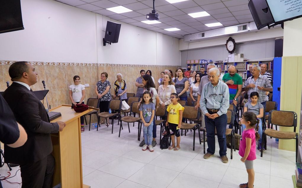 Voorganger ds. Samer Karam (l.) heet gemeenteleden welkom. Het kerkgebouw van de presbyteriaanse gemeente staat in de christelijke wijk Ankawa, in de Koerdische stad Erbil.  beeld Jaco Klamer
