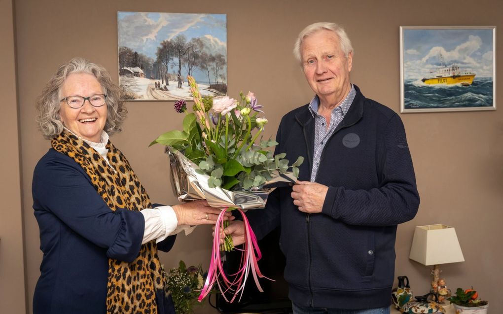 Hennie Lamper-van Gaalen (l.) geeft haar broer Jos van Gaalen een bos bloemen. „Als ik hem voor het raam zie staan, moet ik al lachen om zijn guitige gezicht. Volgens mij wordt iedereen blij van hem.”  beeld Roel Dijkstra