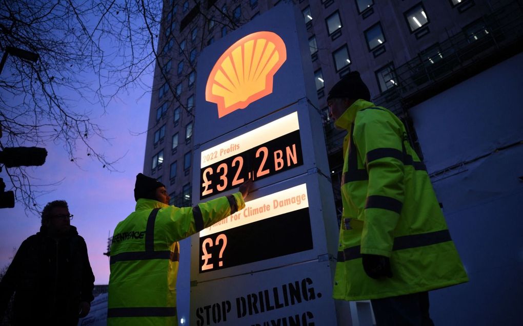 Klimaatactivisten van Greenpeace plaatsen een nagemaakt benzineprijzenbord bij het hoofdkantoor van Shell in Londen. Op het bord de winst van Shell in Britse ponden. beeld AFP, Daniel Leal