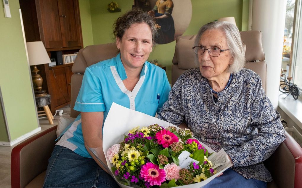 Suus van Antwerpen (r.), bewoner van Woonzorgcentrum Rehoboth, overhandigt Suzanne Slabbekoorn-van der Have een bos bloemen namens diens moeder. beeld Dirk-Jan Gjeltema