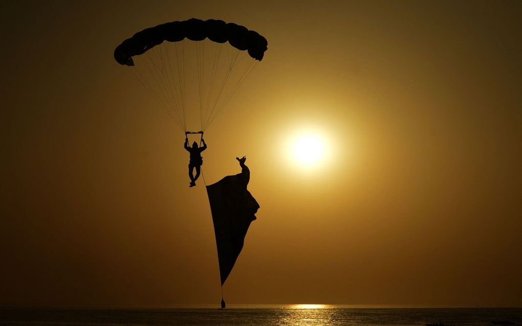 Een parachutist van de Pakistaanse marine neemt deel aan een jaarlijkse oefening in de Arabische Zee bij de havenstad Karachi. beeld AFP, TABASSUM