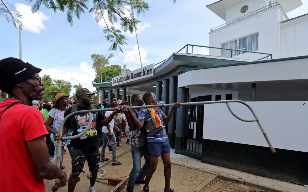 Mensen vallen het parlementsgebouw aan tijdens een protest tegen het economische beleid van de regering in Paramaribo. beeld AFP, Ranu Abhelakh