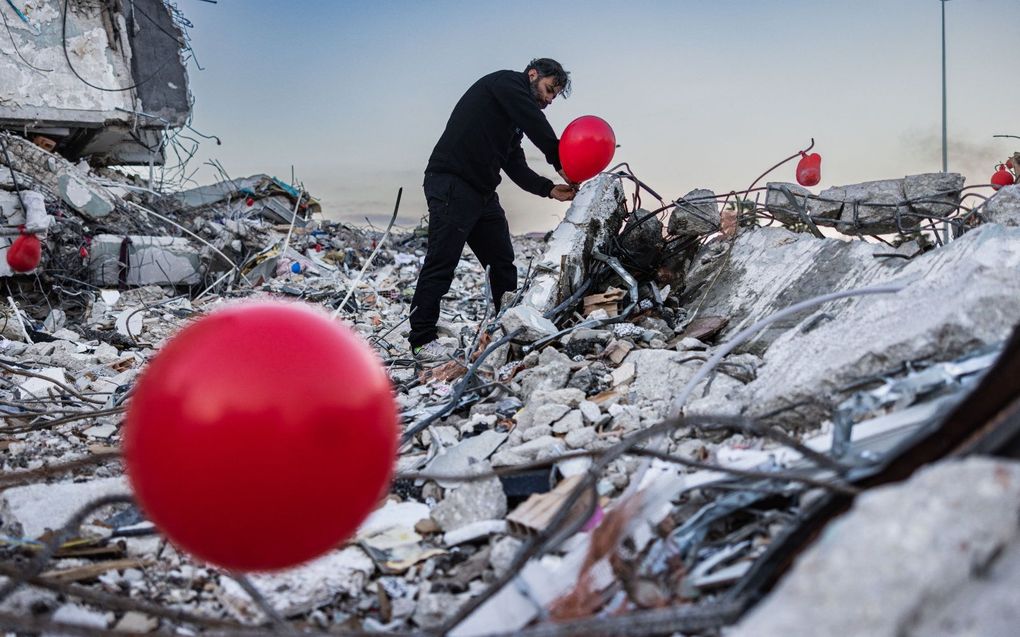 Een man plaatst ballonnen ter nagedachtenis van omgekomen kinderen in het Turkse Antakya. beeld AFP, Sameer al-Doumy