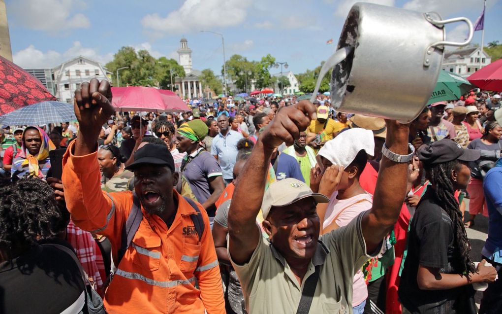 Betogers protesteren bij het parlementsgebouw in de Surinaamse hoofdstad Paramaribo tegen het economisch beleid van de regering-Santokhi. beeld AFP, Ranu Abhelakh