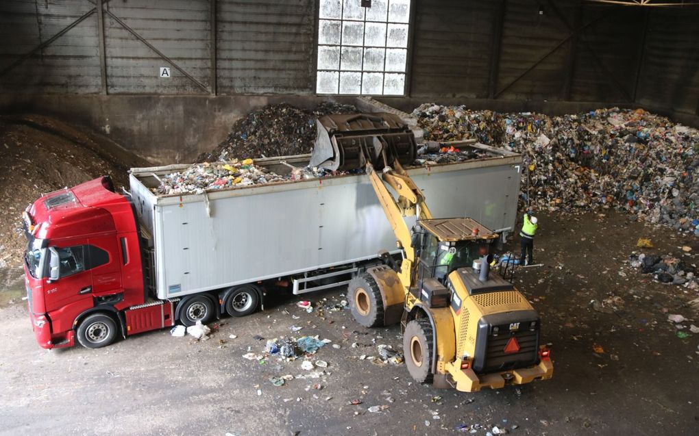 Shovelrijder stort vuilnis terwijl Gerard achter zijn wagen staat. beeld Sjaak van de Groep