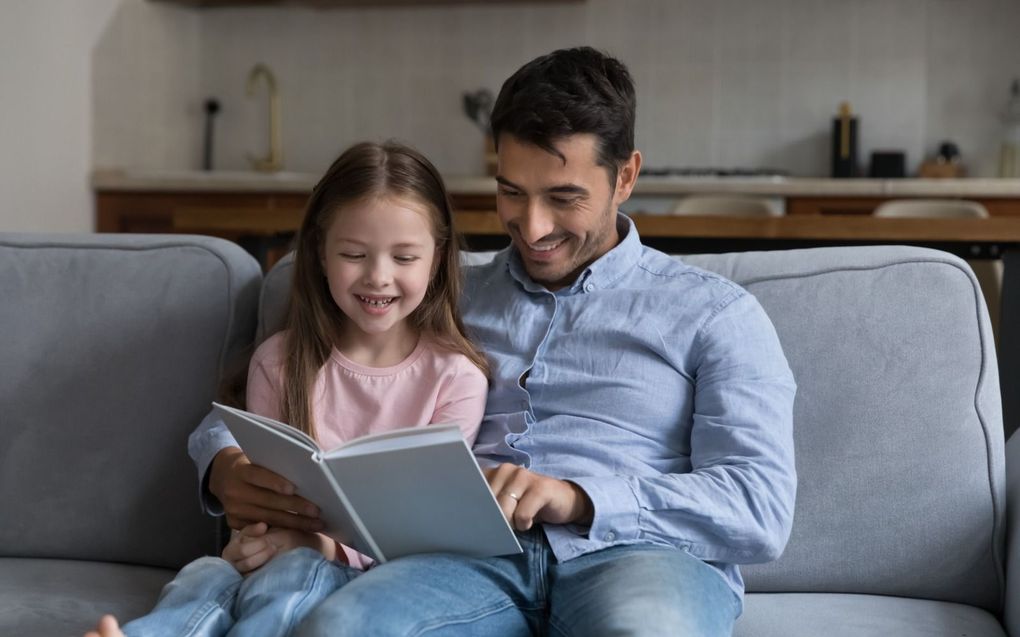 Een vader leest zijn dochter voor; een voorbeeld van belangrijk, onbetaalde arbeid. beeld iStock