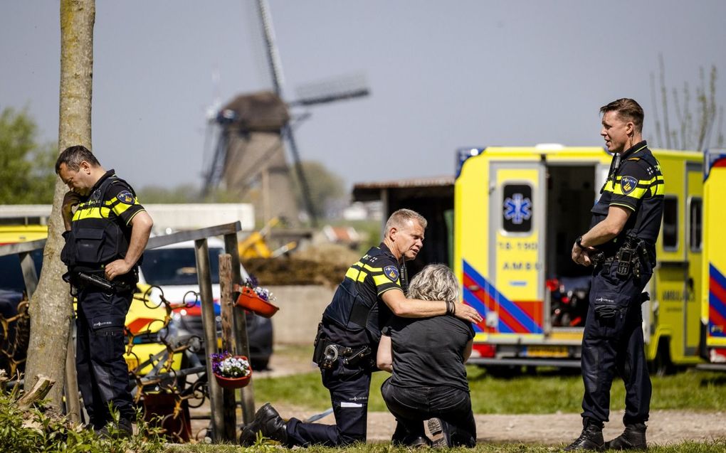 Kort na het schietdrama op de zorgboerderij op 6 mei 2022 in Alblasserdam troost een agent een vrouw. beeld ANP, Sem van der Wal