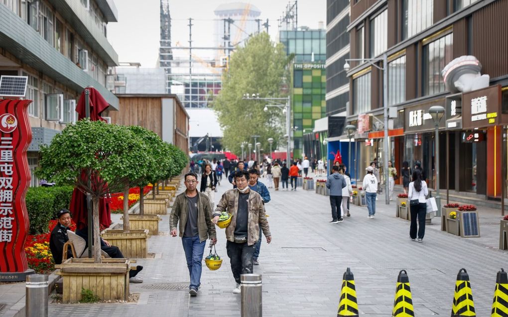 Chinezen lopen maandag in een winkelgebied in de hoofdstad Peking. beeld EPA, Mark R. Cristino