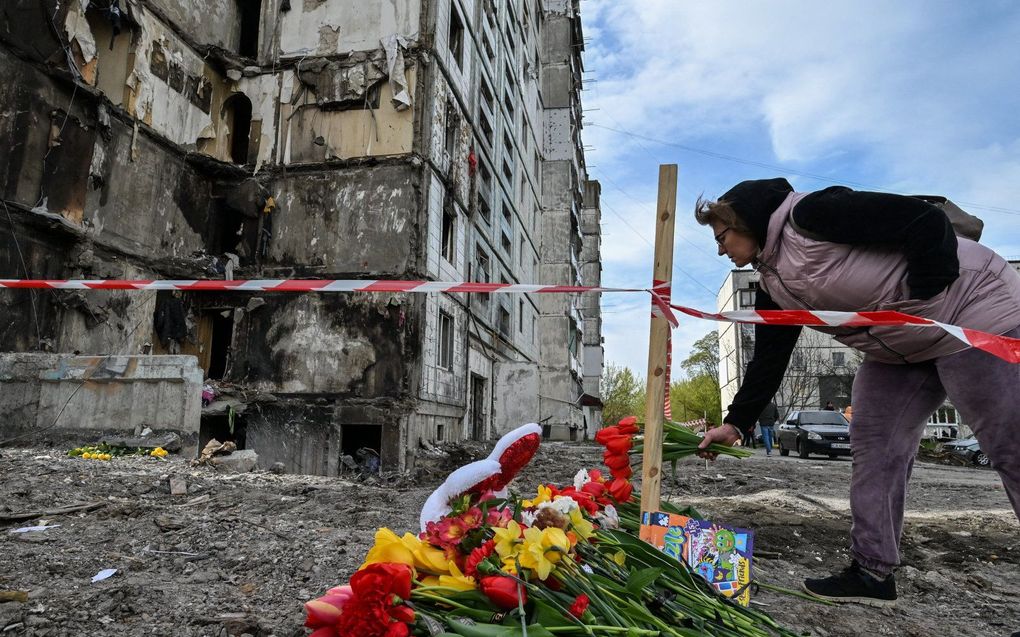 Een vrouw legt bloemen bij een beschadigde flat in Uman na een Russisch bombardement op zondag. beeld AFP, Genya SAVILOV