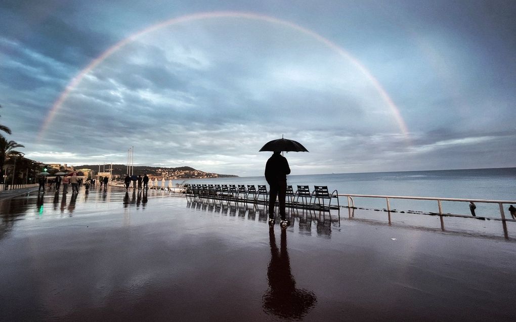 Een man kijkt naar een regenboog op de "Promenade des Anglais" aan de Franse Rivièra stad Nice, Zuid-Frankrijk. beeld AFP, Valery Hache