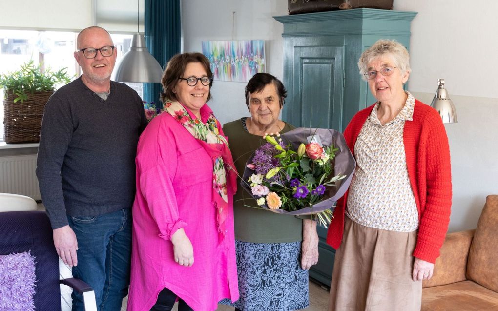 Alie Verwoerd (tweede links) ontvangt een bos bloemen van Reina van der Ham (rechts), omdat ze samen met haar man Bertus (links) veel doet voor haar Oekraïense medemens. beeld RD, Anton Dommerholt