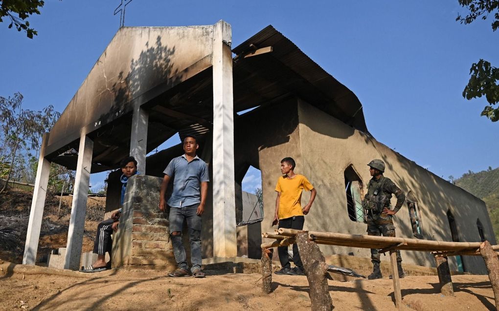 Een militair en een paar dorpsbewoners staan maandag bij een kerk die tijdens etnische onlusten in de Indiase staat Manipur is verwoest. De afgelopen week kwamen zeker 58 mensen bij het geweld in de regio om het leven. beeld AFP, Arun Sankar