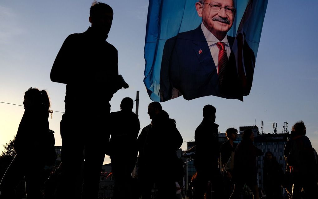 Mensen lopen onder een spandoek waarop presidentskandidaat Kemal Kilicdaroglu staat. beeld EPA, Sedat Suna