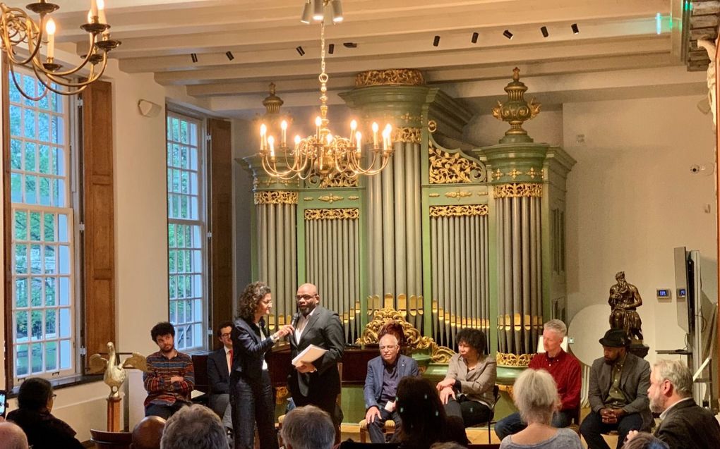 Gespreksleider Kathleen Ferrier (staand, links) geeft dinsdagavond in het Amsterdamse Luthermuseum het woord aan ds. Clifton Walker, predikant van een migrantengemeente in Amsterdam. beeld Arjen Zijderveld