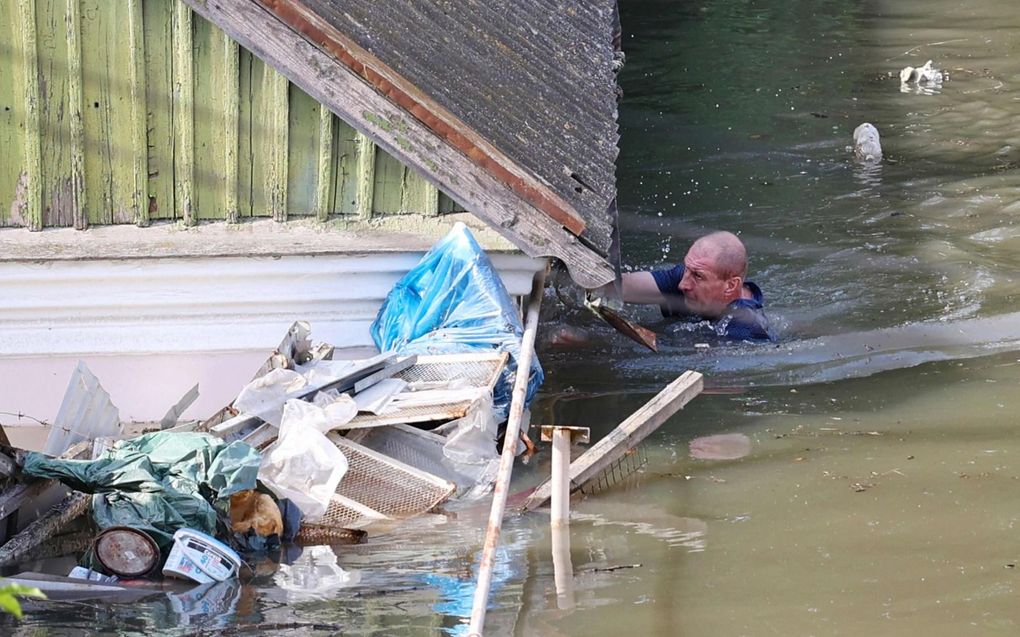 Een Oekraïner zwemt rond zijn huis in de regio Cherson, terwijl het water tot aan de dakgoot reikt door het opblazen van de Kachovka-dam. beeld AFP, Olexander Koryakov