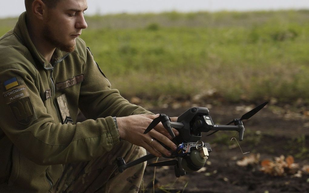 Een Oekraïense militair bedient een drone met een granaat eraan op een onbekende locatie langs de frontlinie. beeld EPA, Alex Babenko