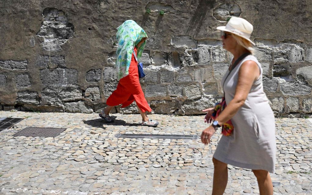 Een vrouw bedekt zichzelf met een sjaal in Avignon, Zuid-Frankrijk. Europa kampt met recordtemperaturen nu een hittegolf over het continent trekt. beeld AFP, Nicolas TUCAT