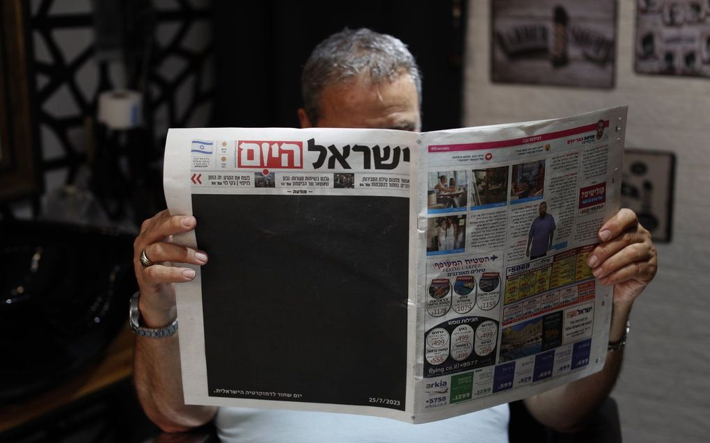 Een Israëlische kapper houdt een exemplaar van de krant 'Israel Hayom' (Israel Vandaag) vast met een zwarte voorpagina en de kop in het Hebreeuws 'Zwarte dag voor de Israëlische democratie'. beeld EPA, Atef Safadi