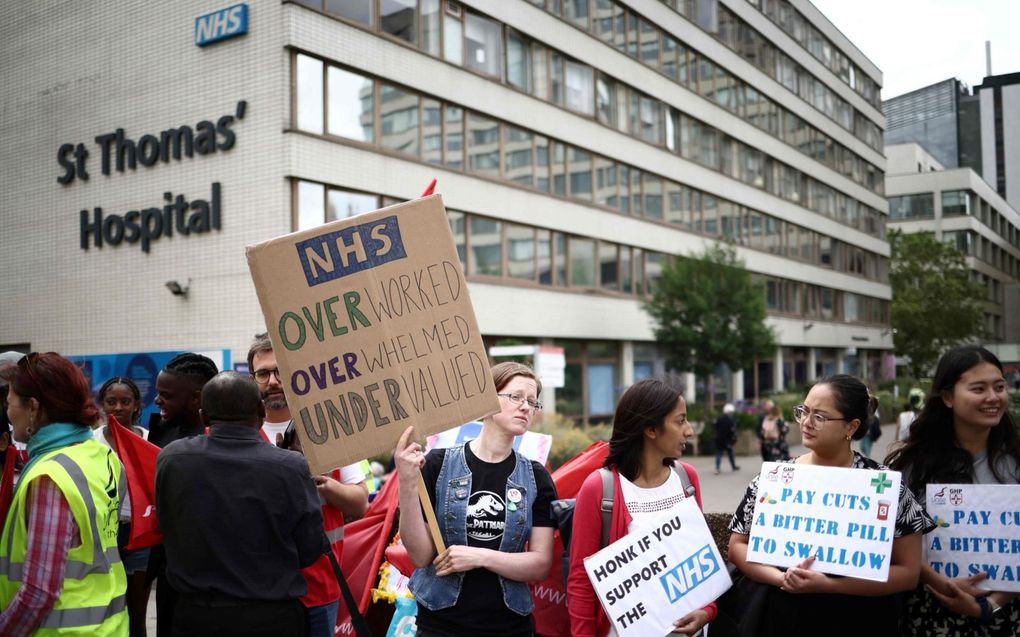 Britse artsen protesteren op 13 juli in een vijfdaagse staking buiten het St Thomas’ Hospital in Londen. Ze zijn ontevreden over de hoge werkdruk in de zorg en het in hun ogen te lage loon dat daar tegenover staat. beeld AFP, Henry Nicholls