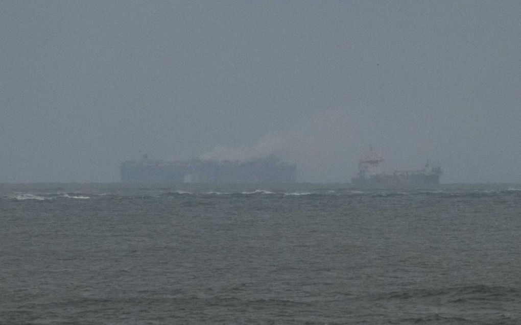 Het schip vanaf het strand in Ameland: geen vlammen meer te zien, maar er komt nog wel rook uit. beeld ANP, Jilmer Postma