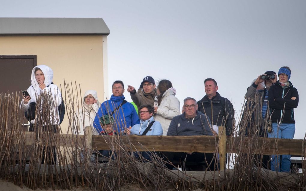 Strandgangers kijken in de richting van de brandende Fremantle Highway op de Noordzee boven Ameland. De brand op het vrachtschip neemt iets af. beeld ANP, Jilmer Postma