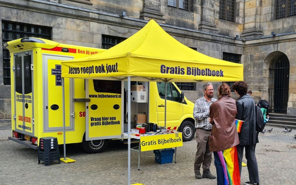 Een vrijwilliger van stichting Sjofar in gesprek met twee bezoekers van de Gay Pride. Sjofar stond zaterdag met twee Bijbelbussen op de Dam in Amsterdam. beeld stichting Sjofar