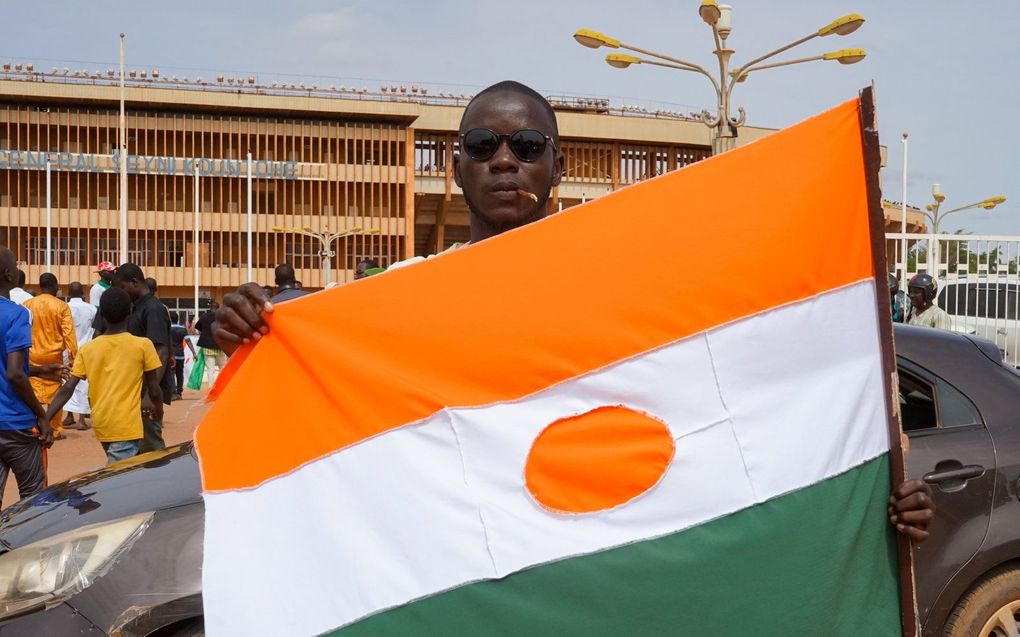 Een man toont een Niger-vlag op weg naar een bijeenkomst in een stadion in Niamey, Niger. Duizenden pro-junta-aanhangers verzamelden zich daar om hun steun te betuigen aan de militaire staatsgreep. beeld EPA, Issifou Djibo