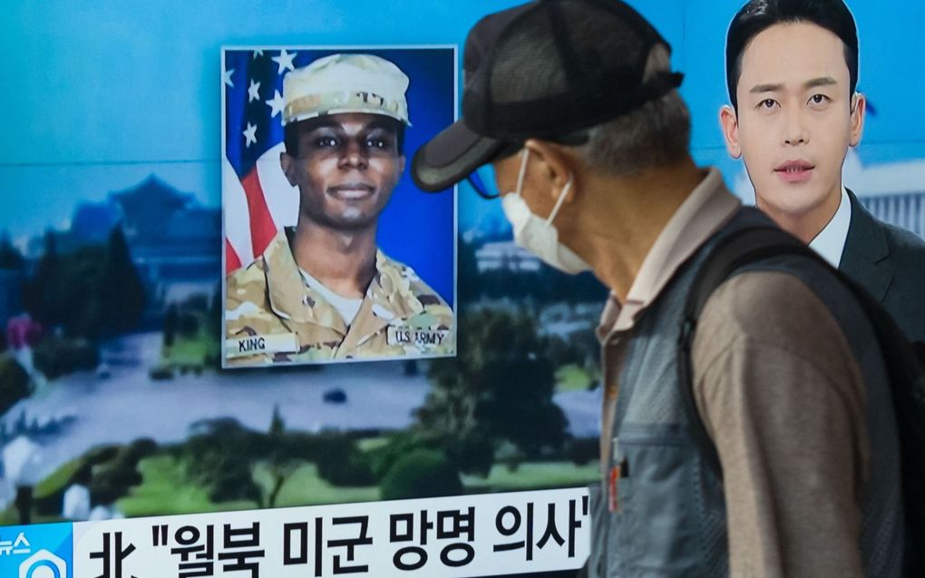 Een man loopt woensdag in de Zuid-Koreaanse hoofdstad Seoul langs een televisie waarop tijdens een uitzending een foto wordt getoond van Travis King. De Amerikaanse militair liep over naar Noord-Korea tijdens een tour. beeld AFP, Anthony Wallace