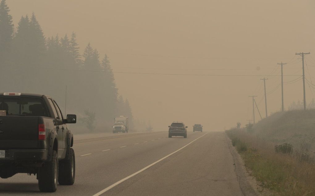 Verkeer rijdt door rook van de bosbranden in Sorrento, British Columbia. Beeld AFP, Paige Taylor White