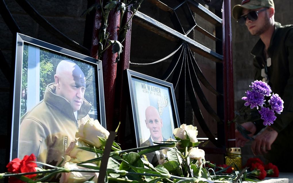 Een Wagnerhuurling legt bloemen bij een herdenkingsplek die is ingericht ter nagedachtenis aan de omgekomen Wagnerbaas Yevgeni Prigozjin en diens legerofficier Dmitri Utkin. beeld AFP, Vladimir Nikolayev