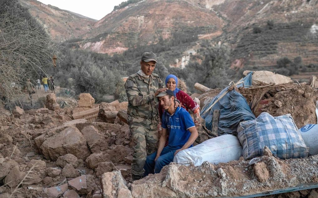 Een Marokkaanse soldaat verzorgt een man die op puin zit in het berggebied van Tizi N'Test, in de provincie Taroudant, een van de zwaarst getroffen gebieden in het door aardbevingen getroffen Marokko. beeld AFP, BULENT KILIC