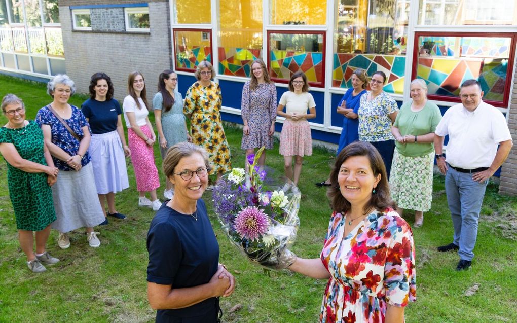 Tineke Kempeneers (l.) geeft een bloemetje aan collega Marianne Boonzaaijer, die 31 juli 25 jaar in dienst was. Op de achtergrond andere personeelsleden van de Petrus Datheenschool. beeld RD, Anton Dommerholt